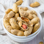 Peanuts in shell in a bowl on a white background.