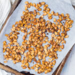Roasted acorn squash seeds on a baking tray with parchment paper.