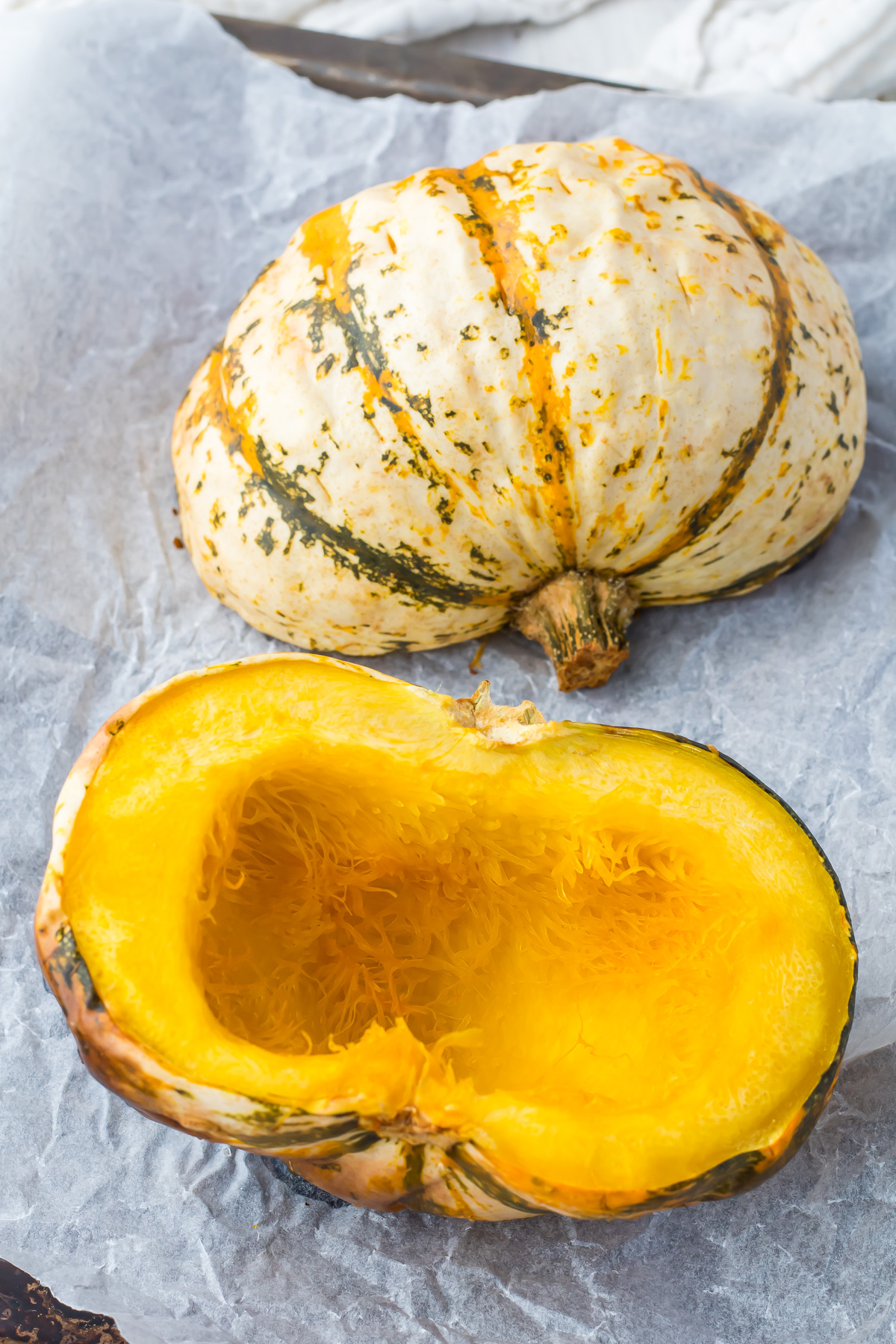Two roasted carnival squash halves on a baking tray.