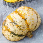 A roasted carnival squash half on a baking tray.