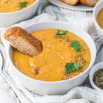 A bowl of lentil soup with ham topped with bread.