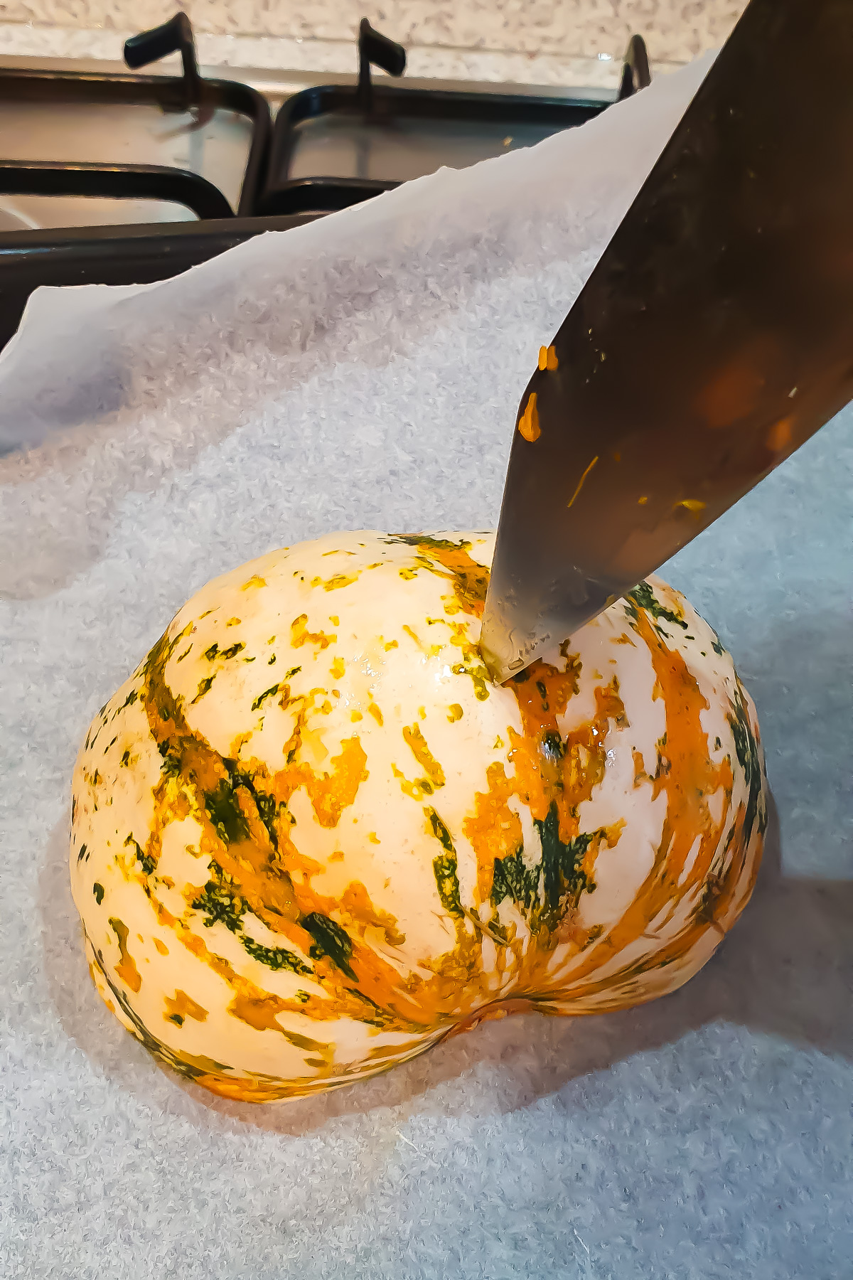 A knife piercing a carnival squash.