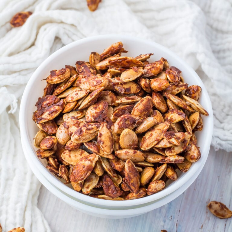 Sweet roasted pumpkin seeds in a white bowl.