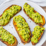 Five sweet potato avocado toast slices sprinkled with sesame seeds on a white plate.