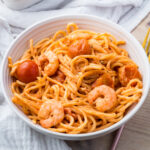 A bowl of shrimp feta pasta placed on a light-colored cloth.