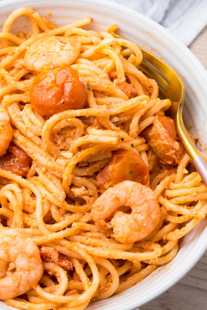 Shrimp feta pasta served in a white bowl with a gold fork.