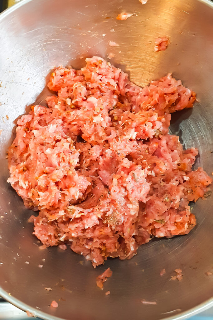 Raw ground turkey sausage meat in a metal mixing bowl.