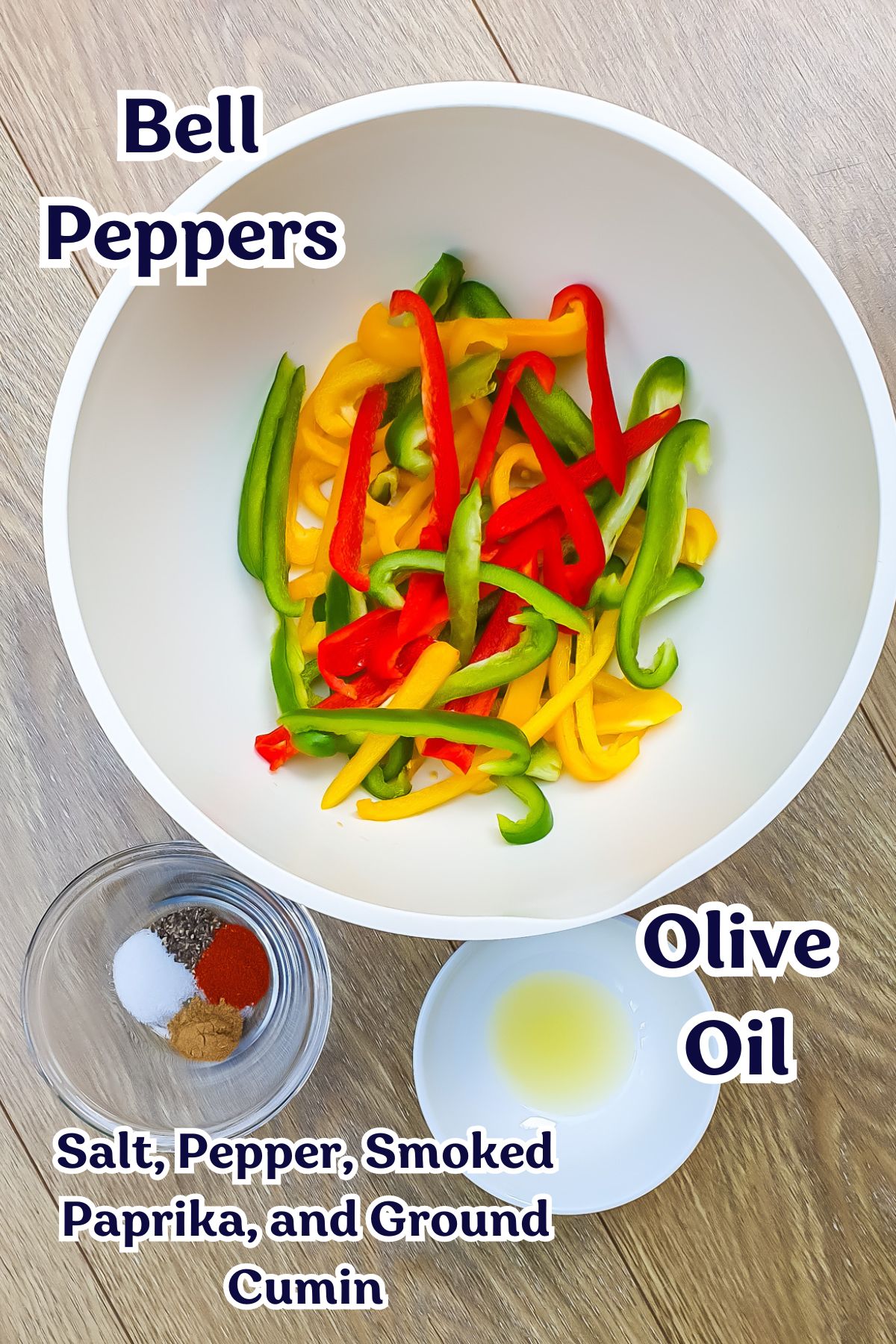 A bowl of sliced red, yellow, and green bell peppers, with separate small bowls containing olive oil and seasonings (salt, pepper, smoked paprika, and ground cumin) on a wooden surface.