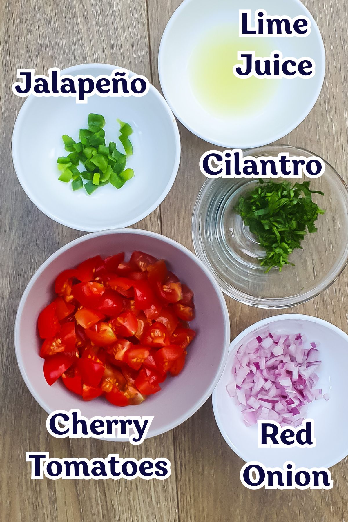 Five bowls on a wooden surface contain chopped jalapeño, cherry tomatoes, red onion, cilantro, and lime juice, each labeled with text.