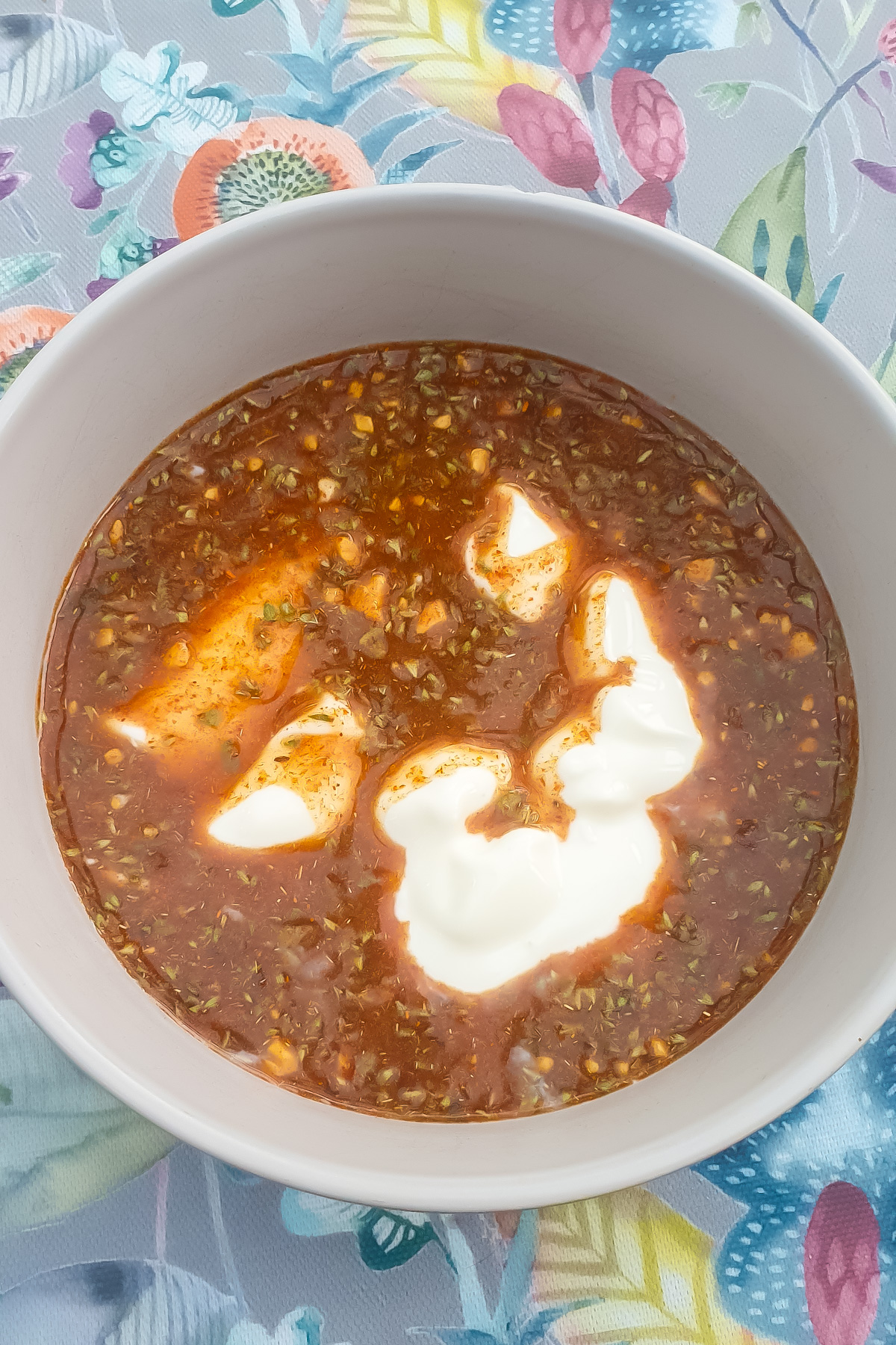 A bowl of ingredients, placed on a floral-patterned tablecloth.
