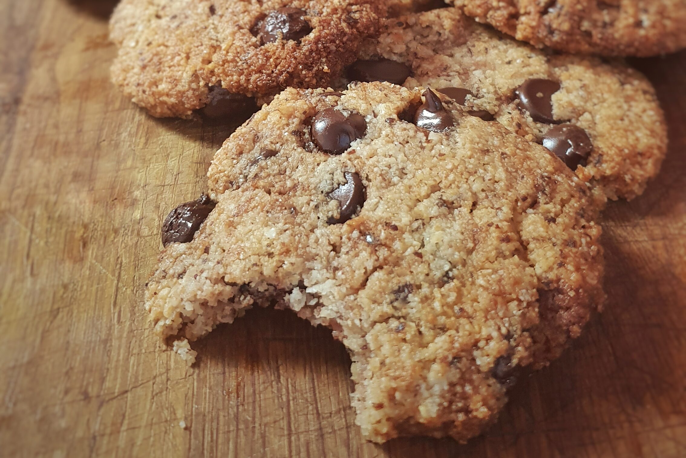 Chocolate chip cookies on wooden board with glass of almond milk