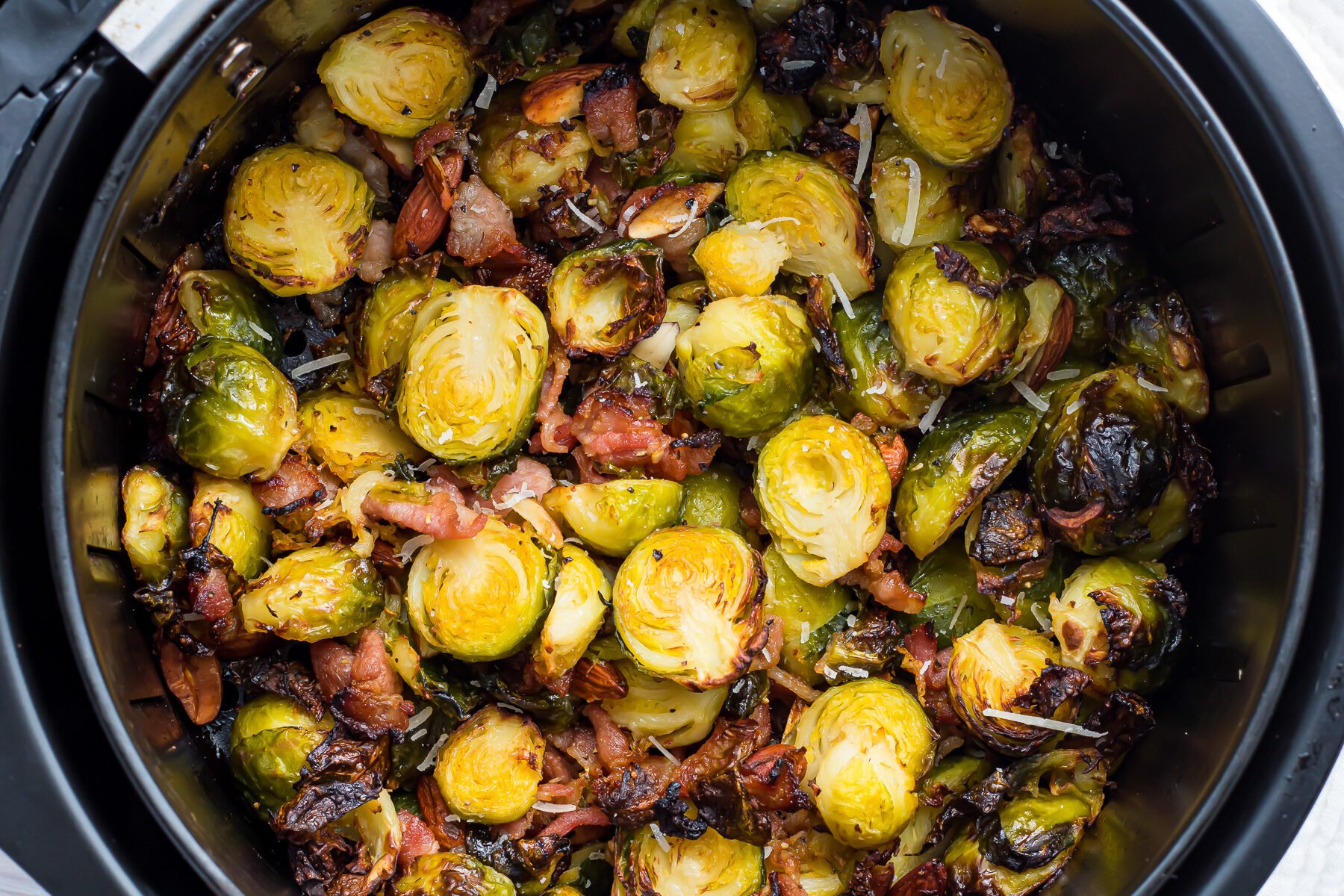 Overhead shot of brussels sprouts with bacon in an air fryer.