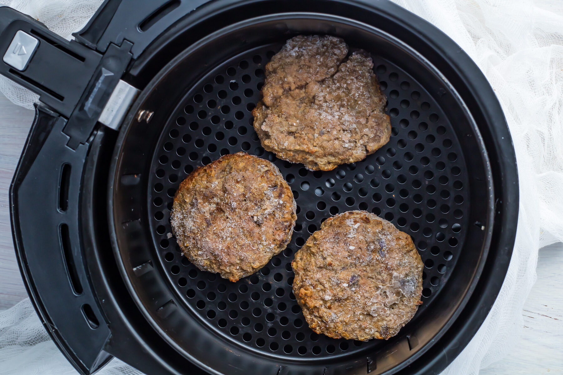 Frozen burgers in an air fryer.