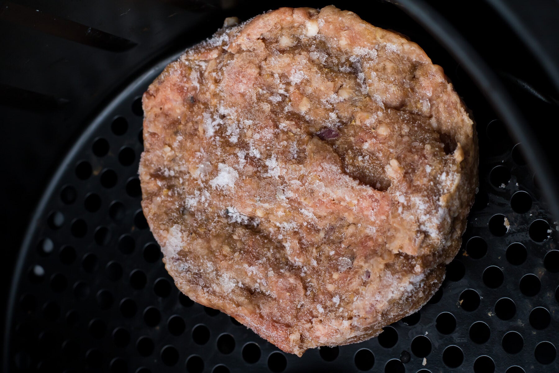 Frozen hamburger in an air fryer.