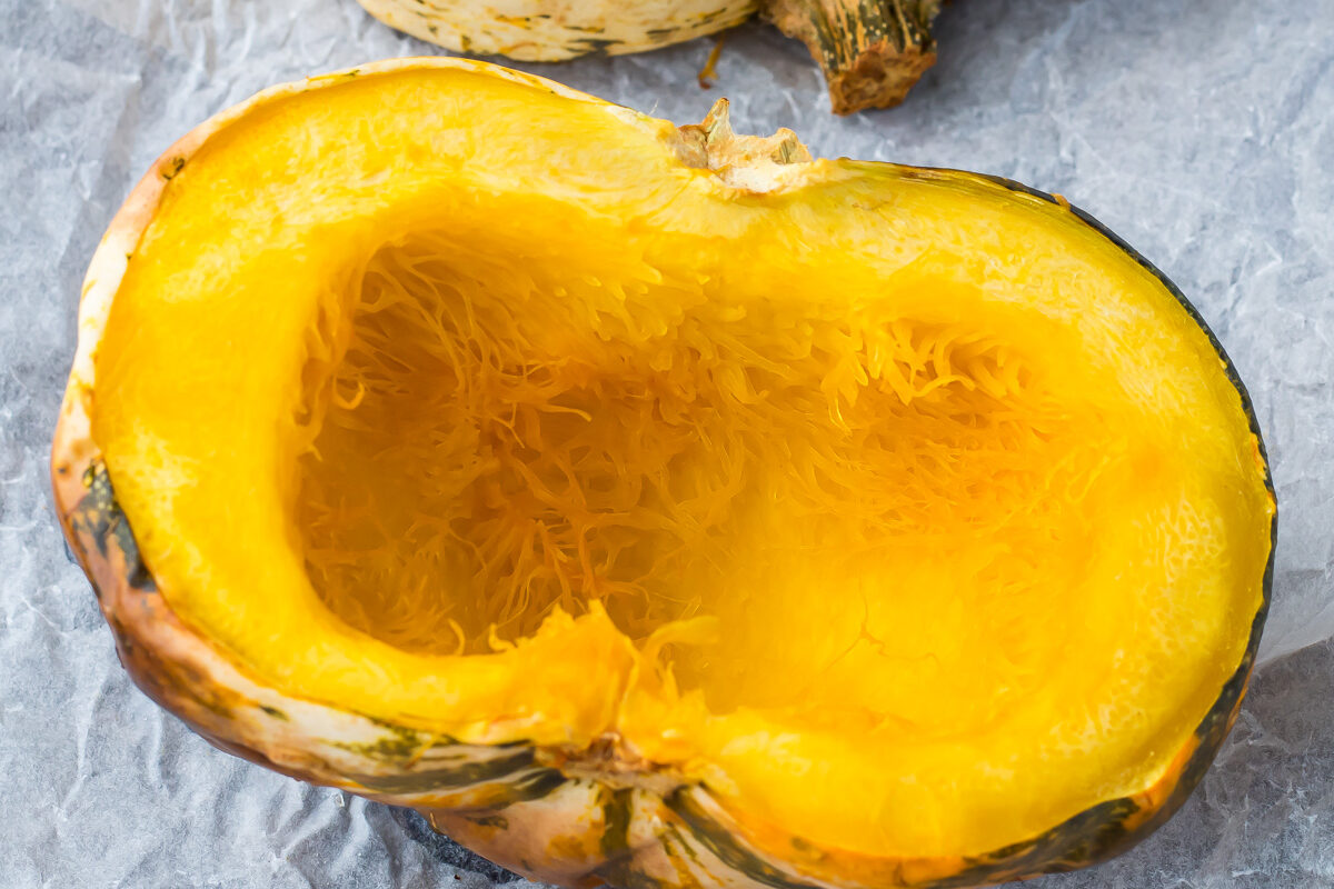 Two roasted carnival squash halves on a baking tray.