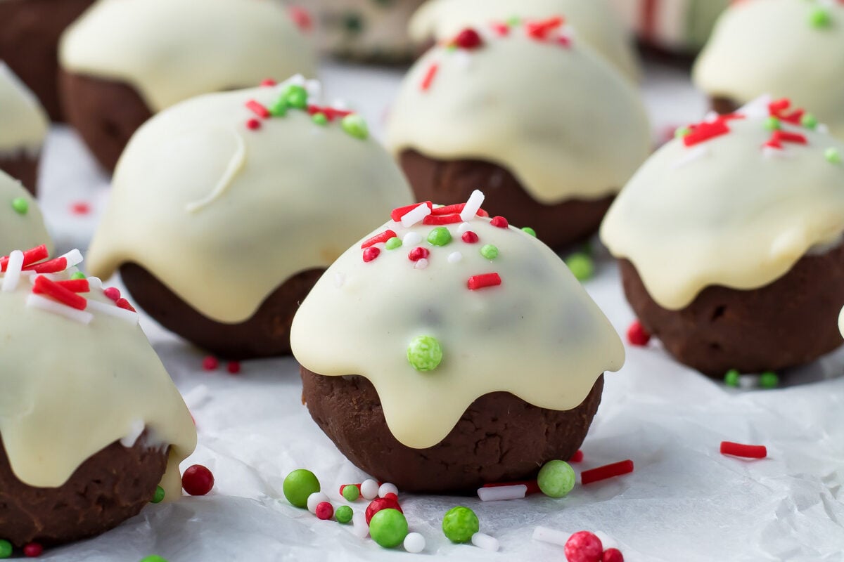 A plate of Christmas cookies decorated with chocolate truffle icing and festive sprinkles.