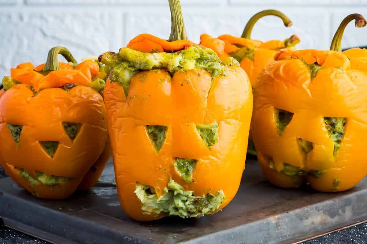 Halloween mac and cheese mac o lanterns on a baking tray in front of a white wall.