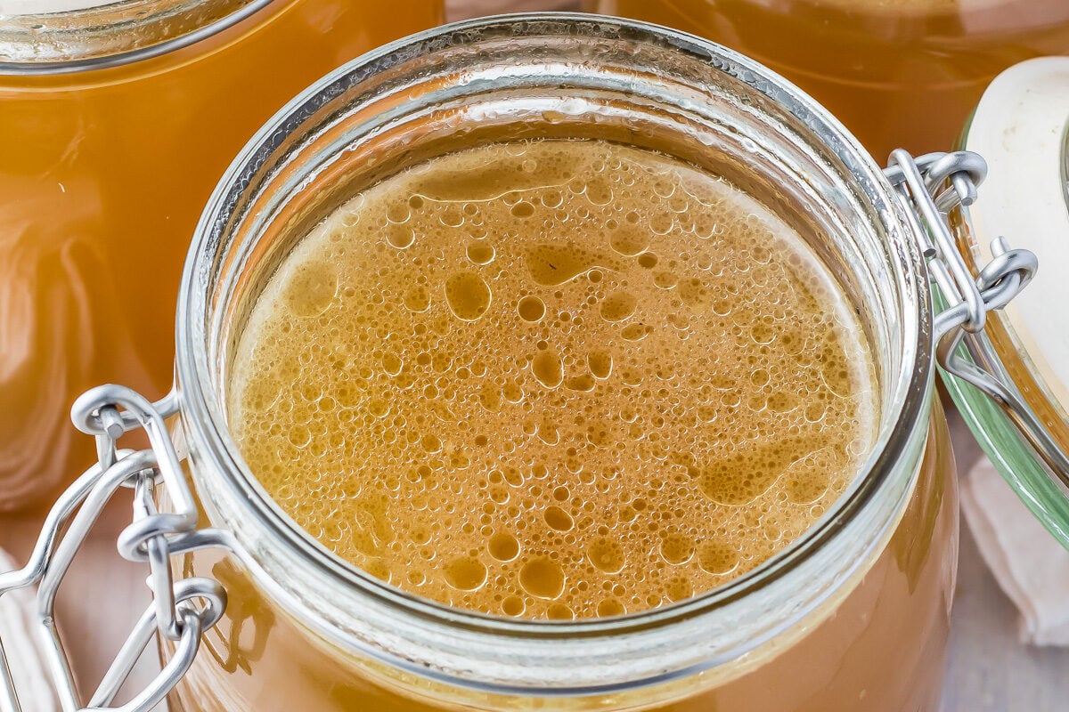 Three jars of ham stock, one with the lid open.