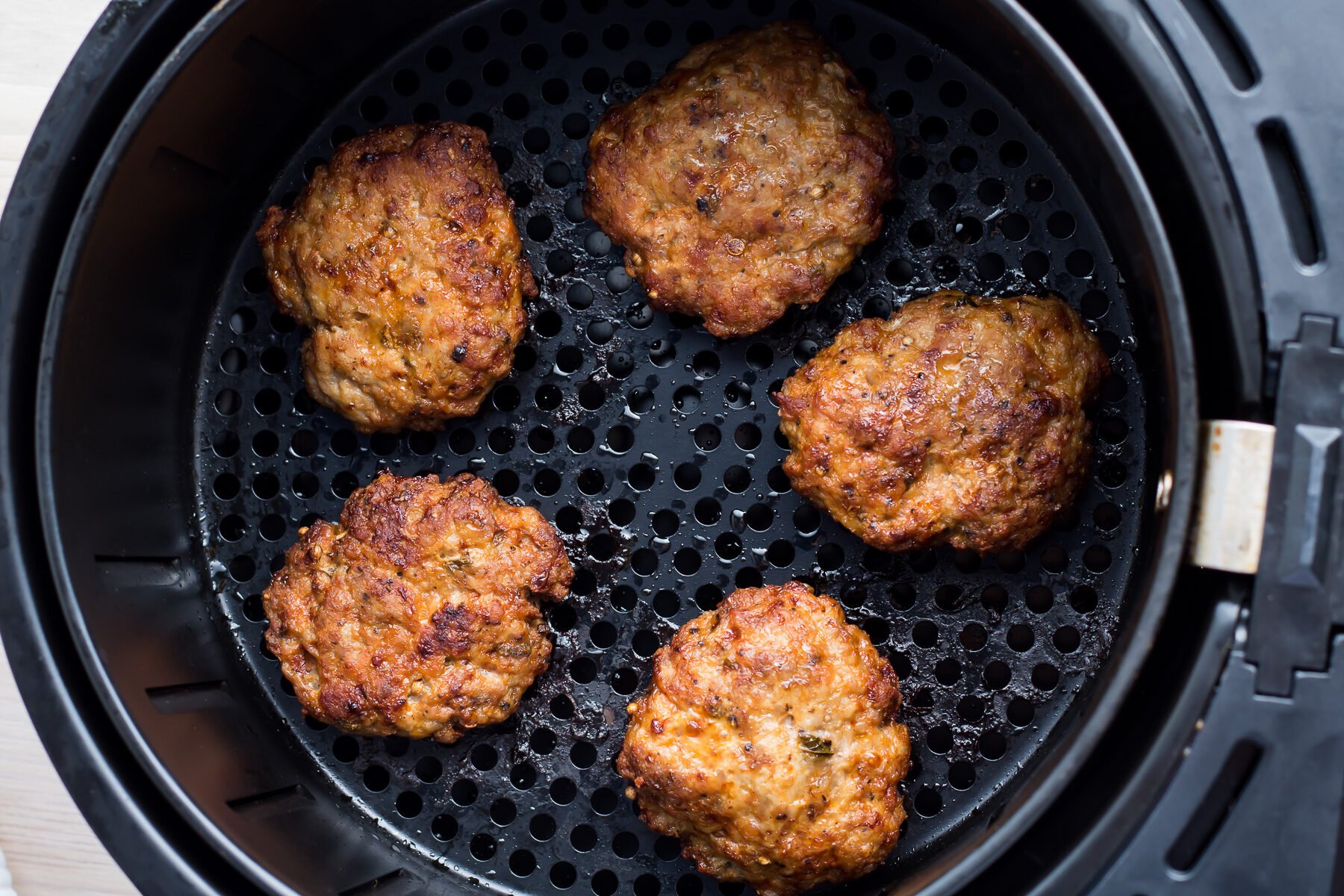 Overhead photo of breakfast sausage patties in an air fryer.
