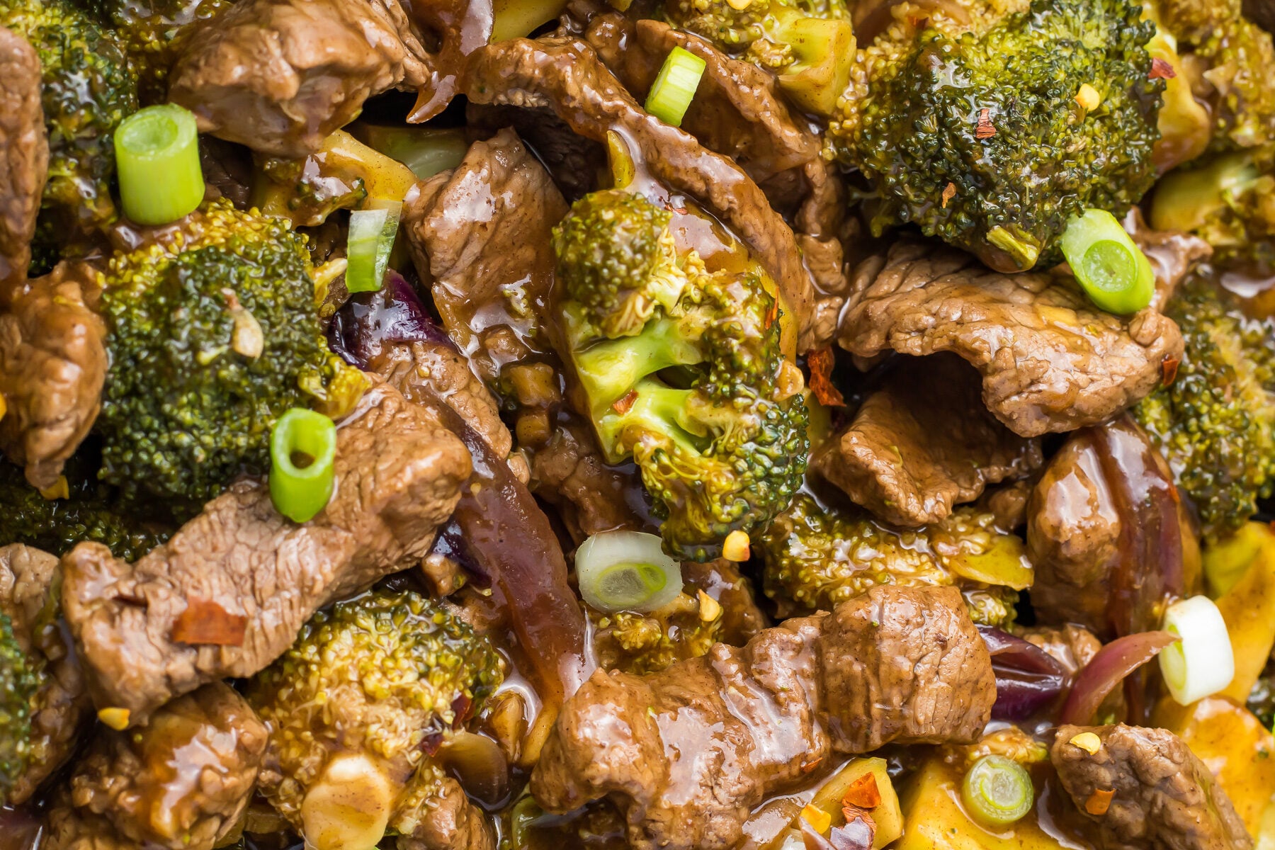 A close up of beef and broccoli in a sauce.