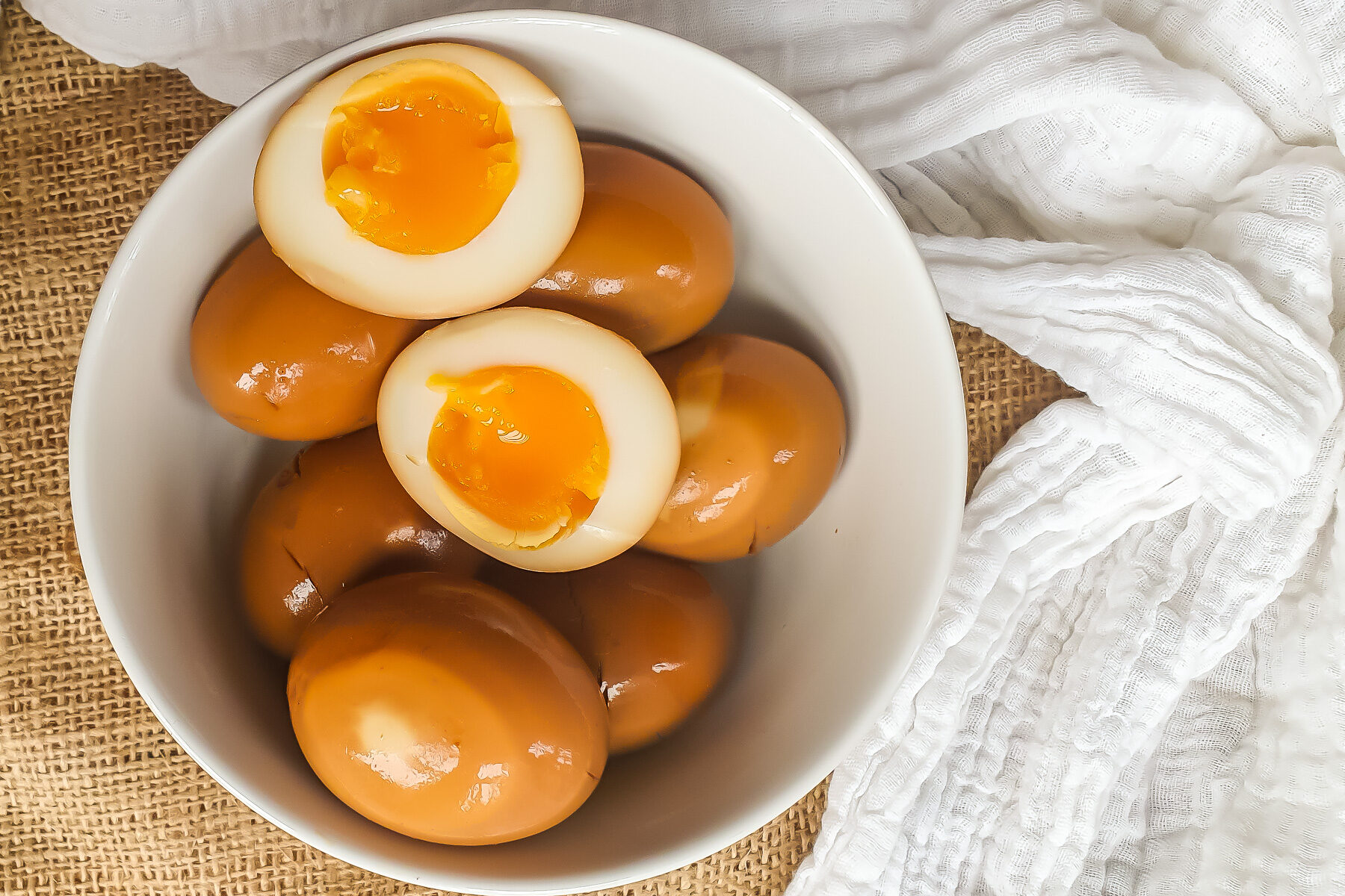 Overhead shot of ramen eggs in a white bowl.