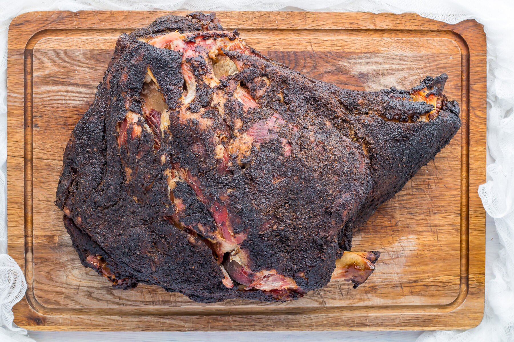 Overhead shot of Smoked pork shoulder on a wooden chopping board.