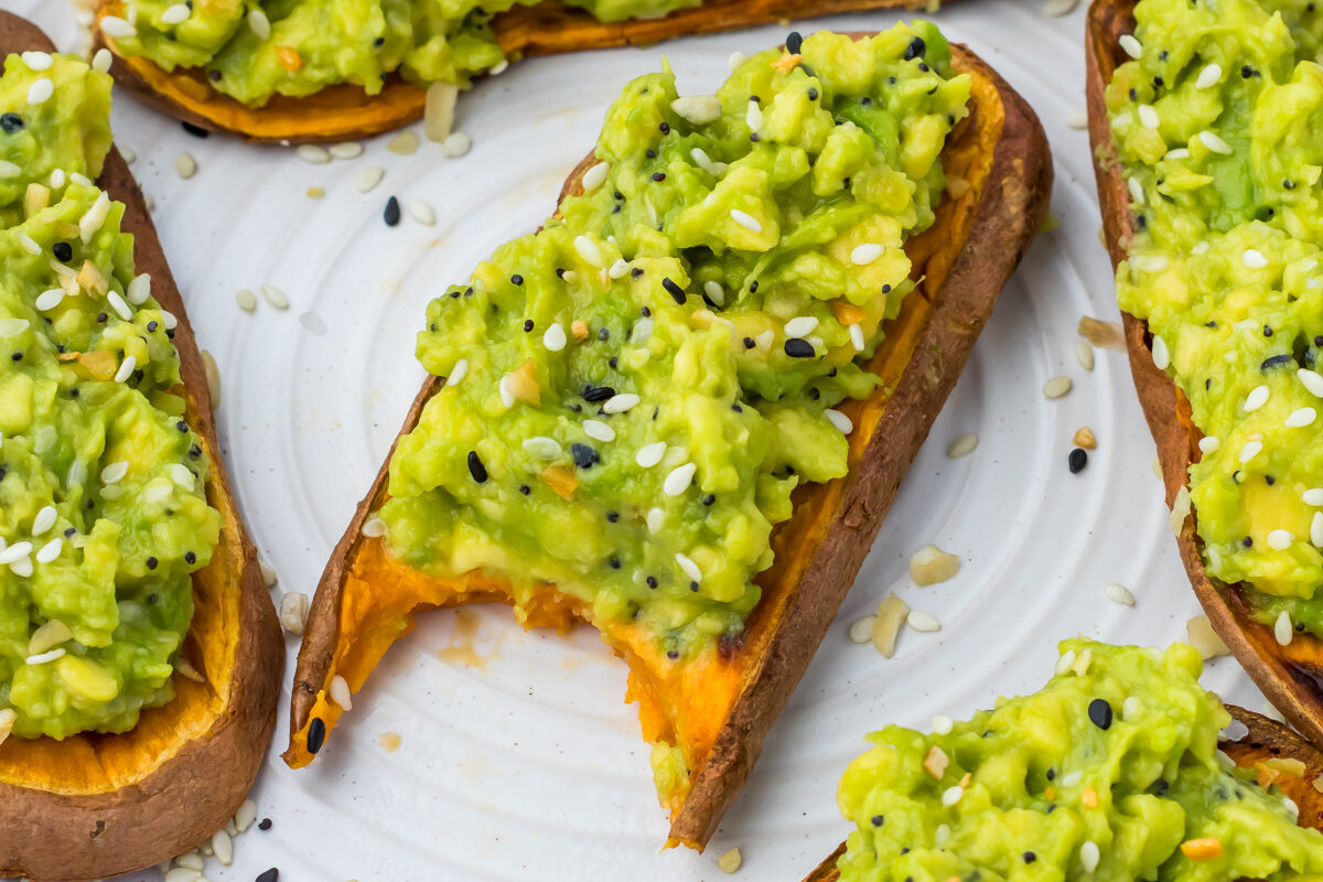 Slices of sweet potato avocado toast sprinkled with sesame seeds on a white plate.