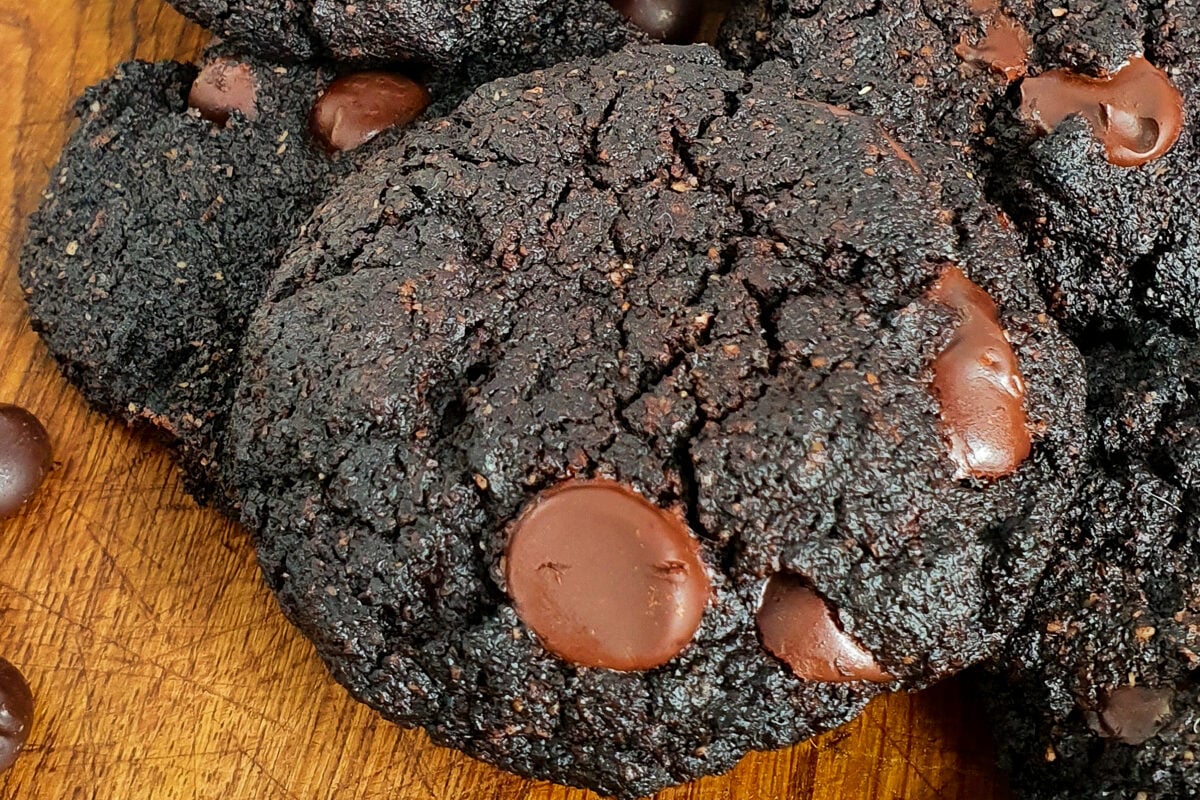 Double Chocolate Cookies on wooden chopping board with glass of milk