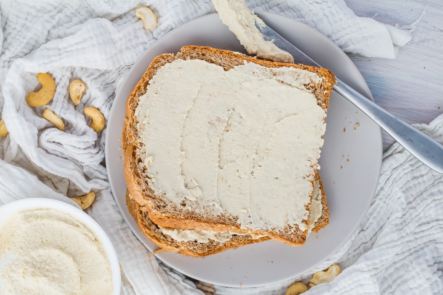 Overhead photo of vegan cream cheese on bread on a grey plate.