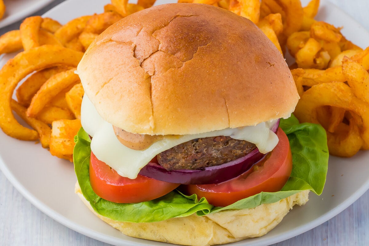 Worcestershire sauce burgers on grey plates with curly fries.