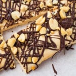 A close-up of frozen cottage cheese bark topped with chopped peanuts and drizzled with dark chocolate on parchment paper.
