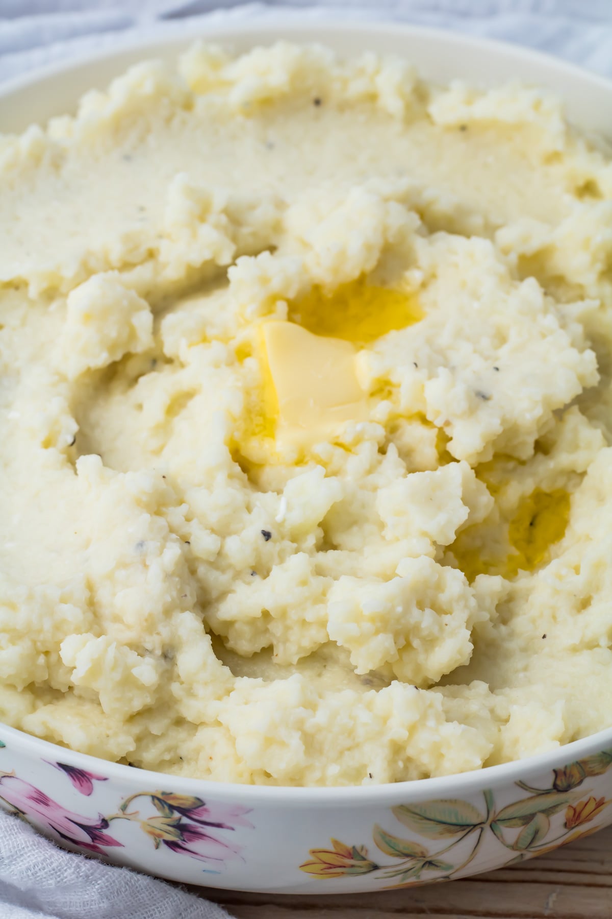 A bowl of cauliflower mash with a pat of melting butter on top.