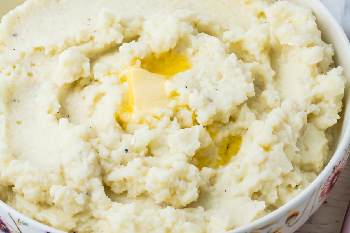 Bowl of cauliflower mash with a pat of melting butter on top.