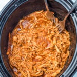 Shredded slow cooker chicken taco meat in a slow cooker with two forks, ready to serve.