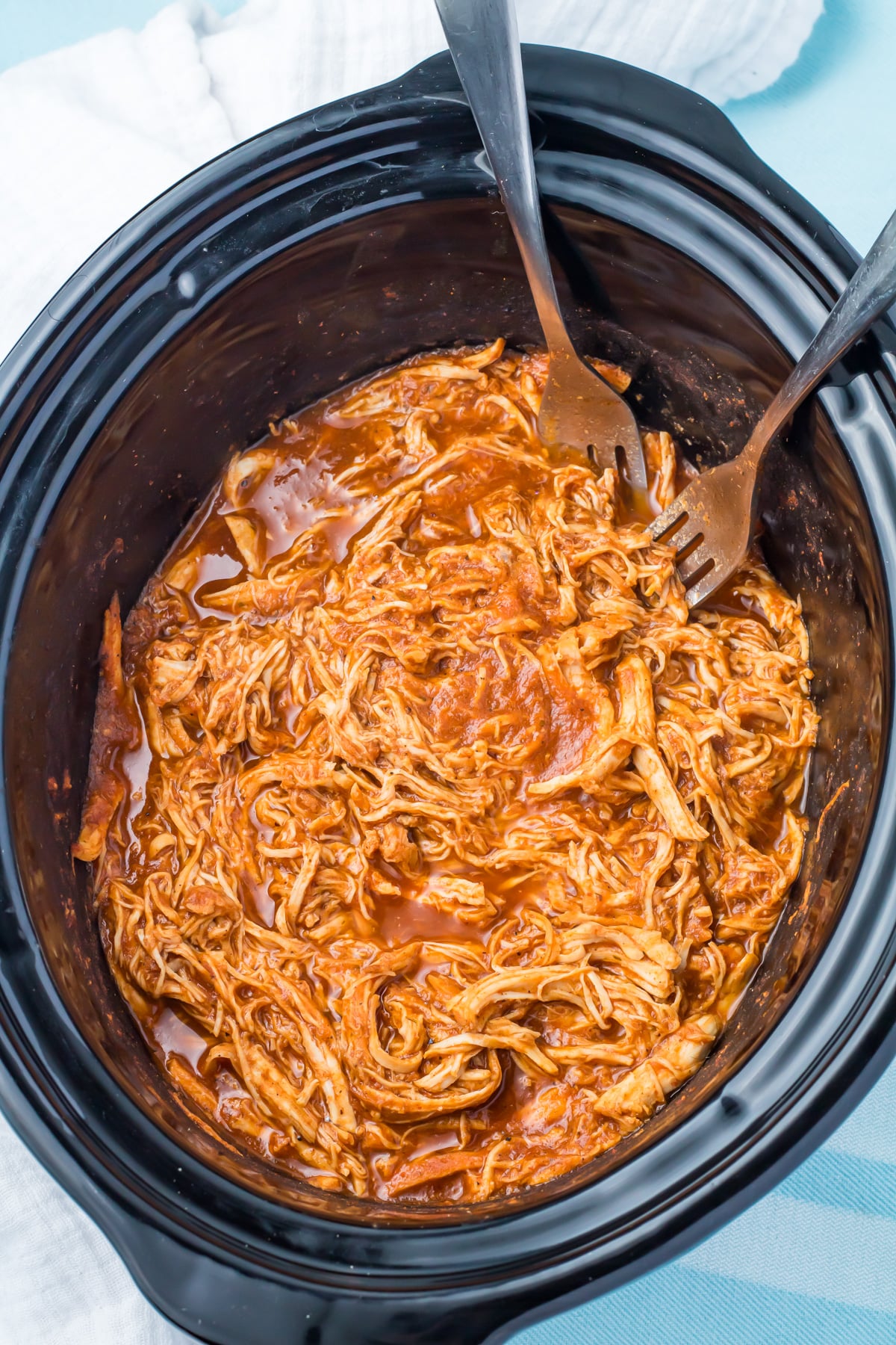 Shredded slow cooker chicken taco meat in a slow cooker with two forks, ready to serve.