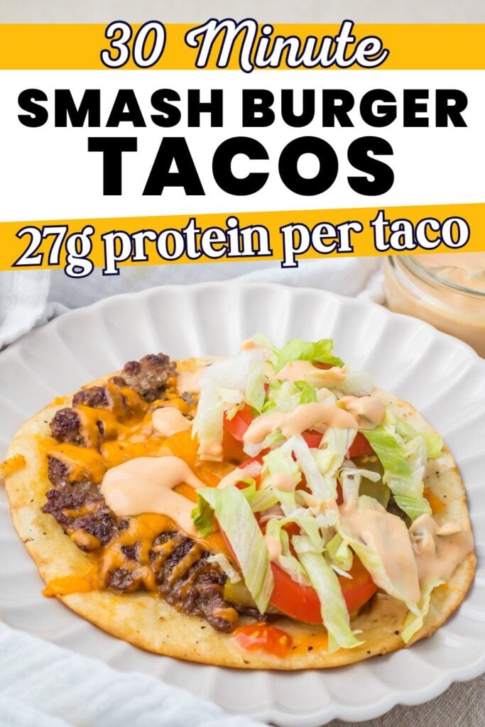 A smash burger taco topped with lettuce, tomato, and sauce on a white plate, with text about 30-minute prep and 27g protein per taco.