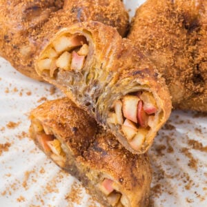 Close-up of sliced air fryer apple donut with visible apple filling and a golden-brown pastry crust, topped with a dusting of brown sugar cinnamon.